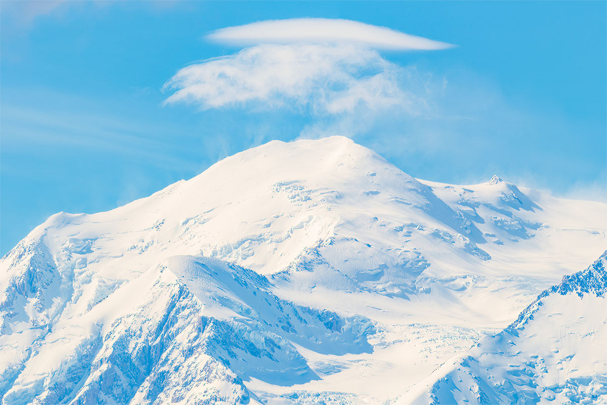 Denali summit beneath a lenticular cloud with wind-blown snow in Denali National Park